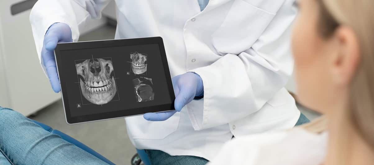 dentist holding cbct image and showing patient