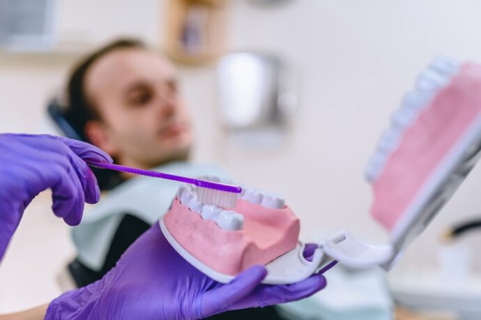 dental hygienist demonstrating how to brush teeth on a model mouth