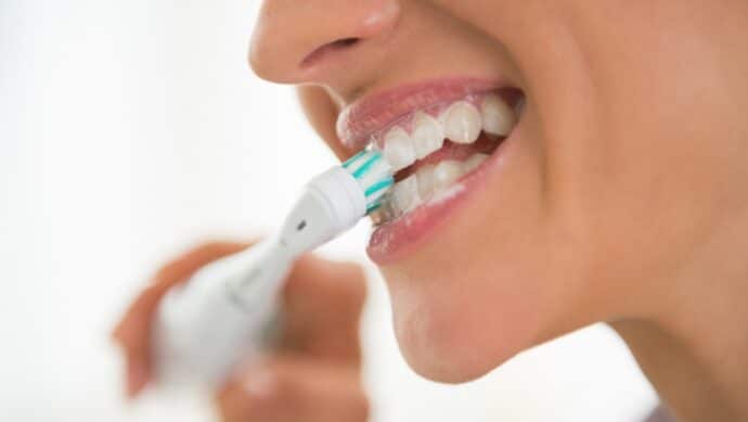 woman brushing teeth with an electric toothbrush