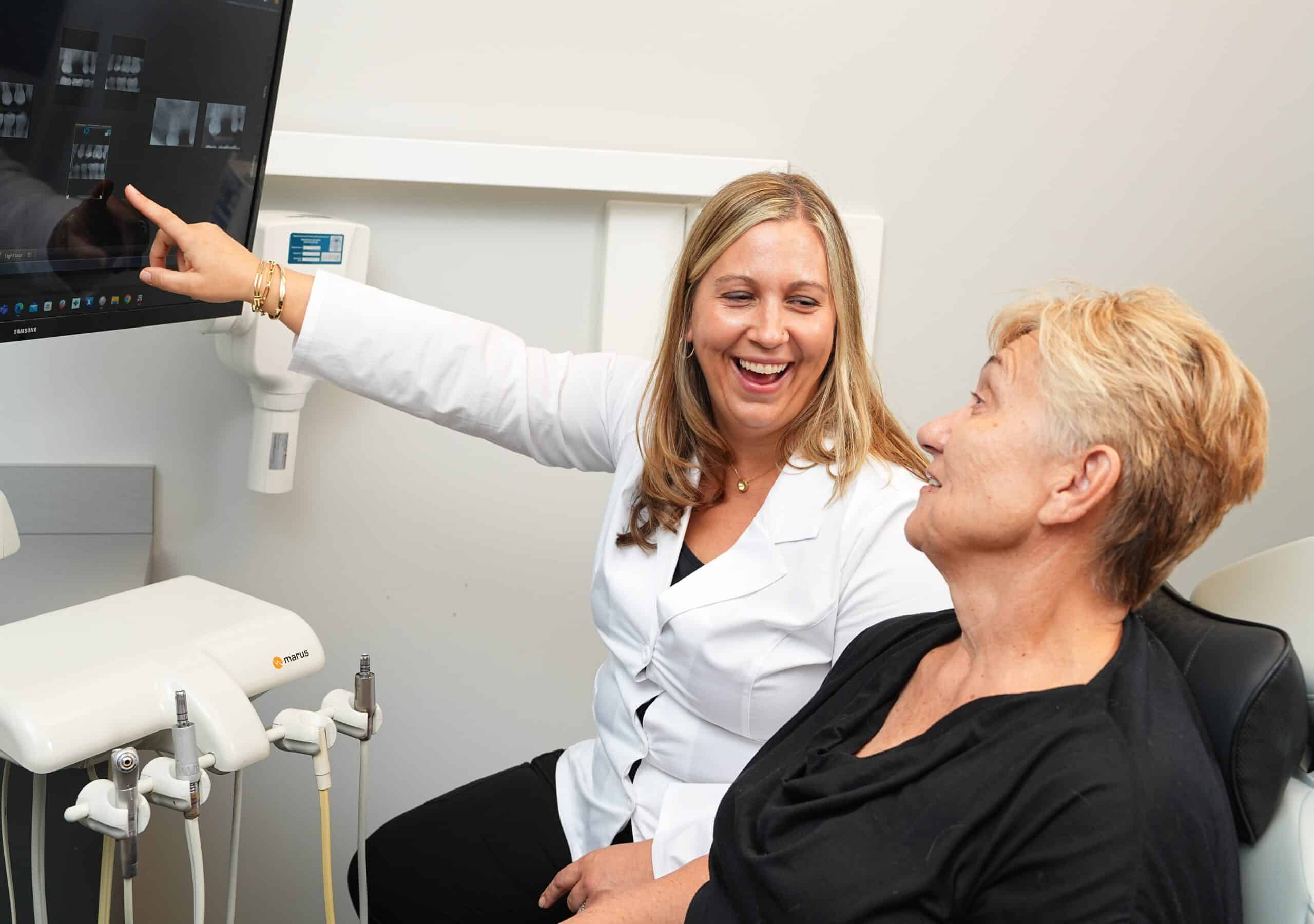 Dr. Hedrick reviewing dental X-rays on a monitor with a patient during an oral surgery consultation at Longmont Dental Loft.